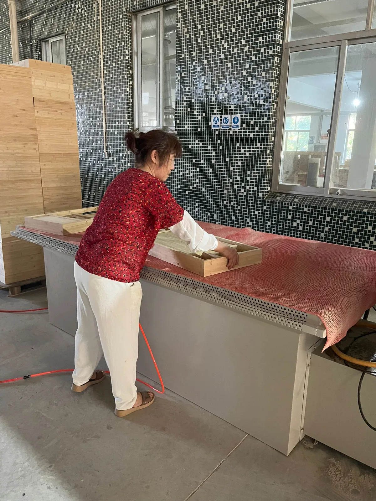 Worker blowing dust off a finished wooden box on a workbench with an air gun