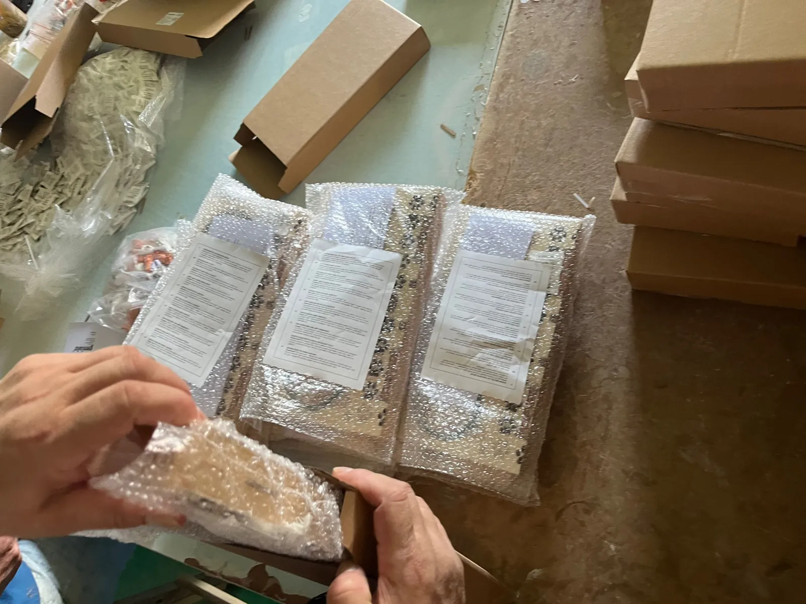 Hands packing finished wooden pieces in plastic bags with instruction sheets