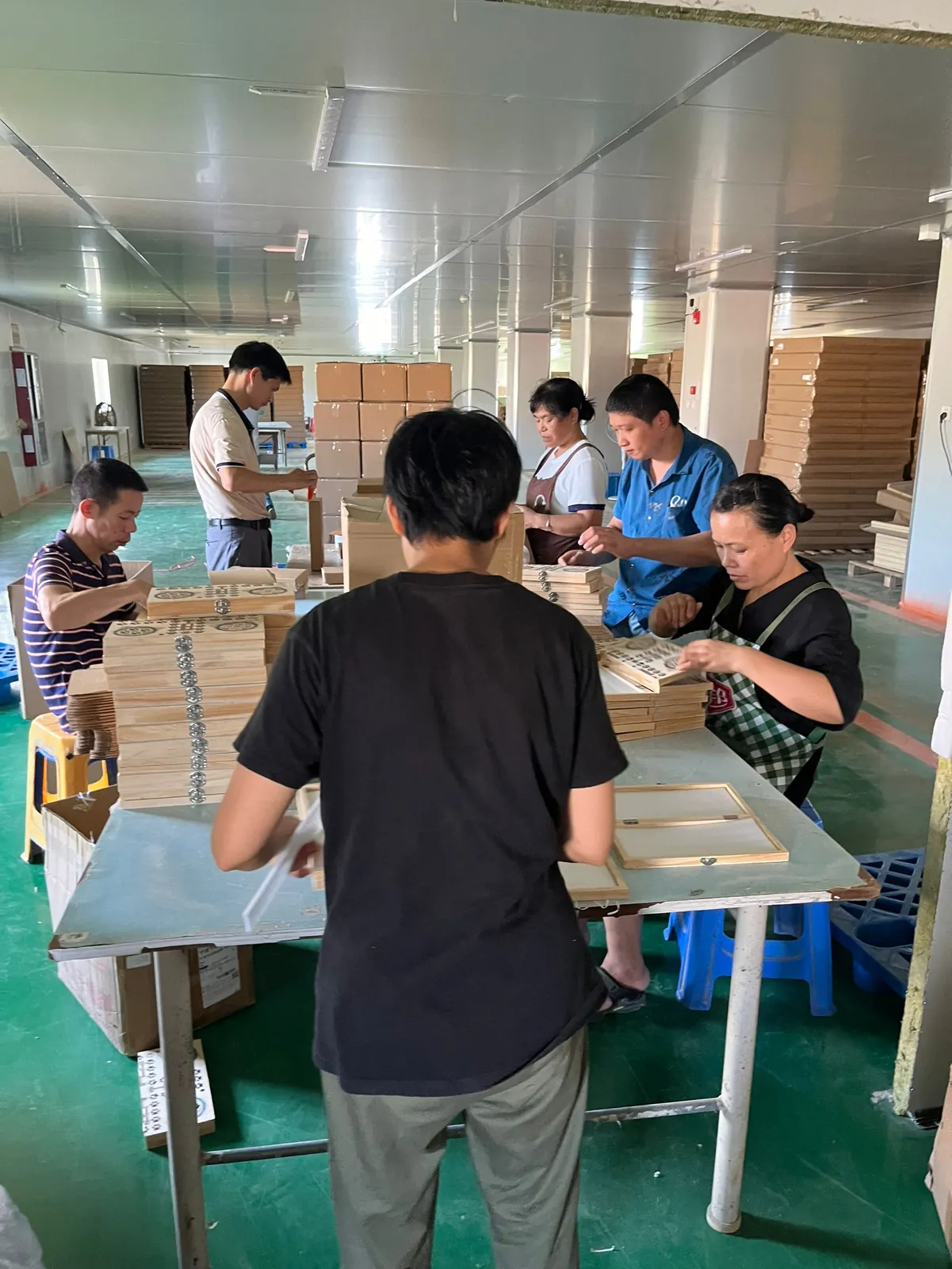 Packing team wrapping and boxing finished goods at a long table