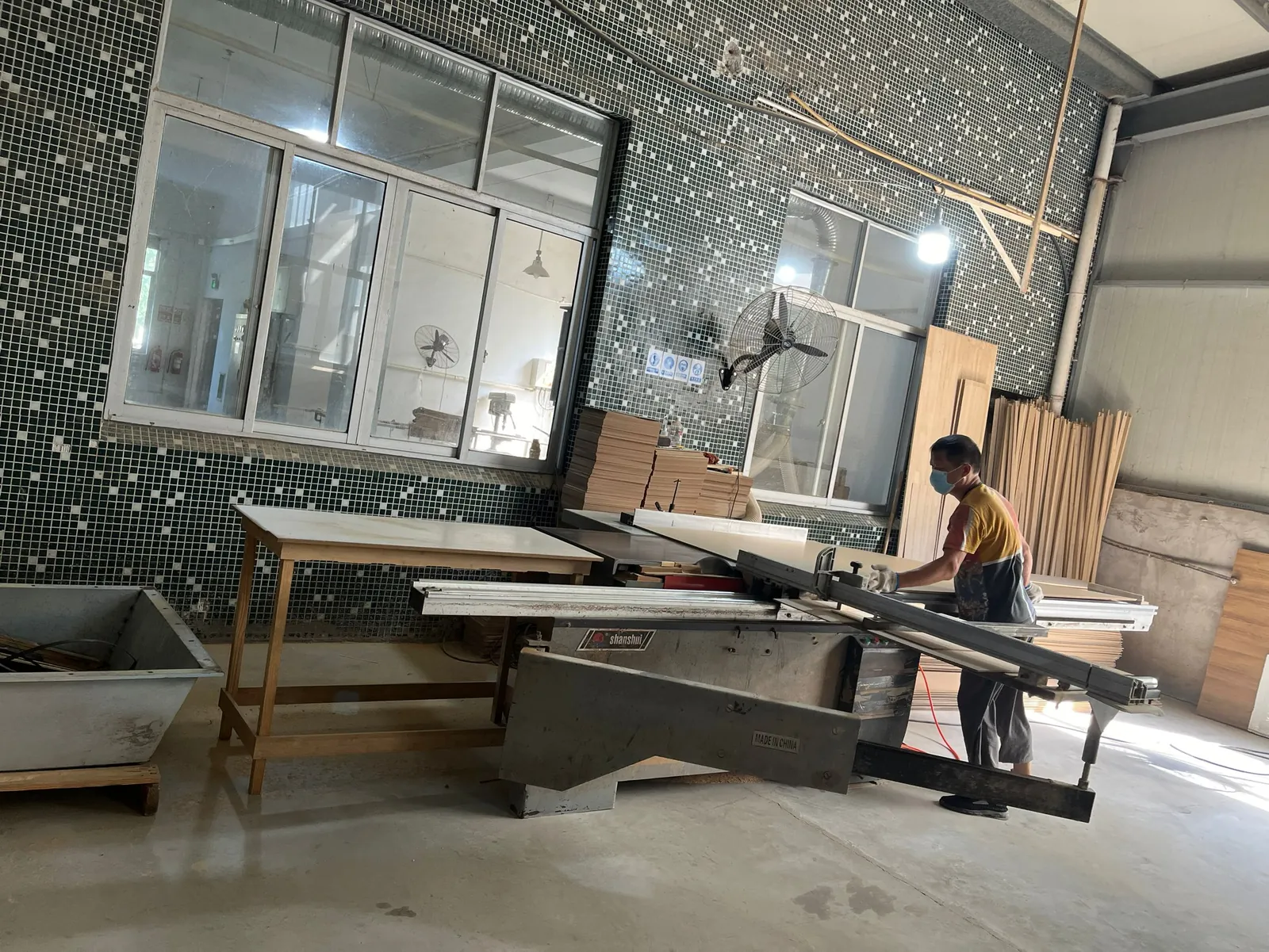 Operator working at a sliding panel saw cutting boards
