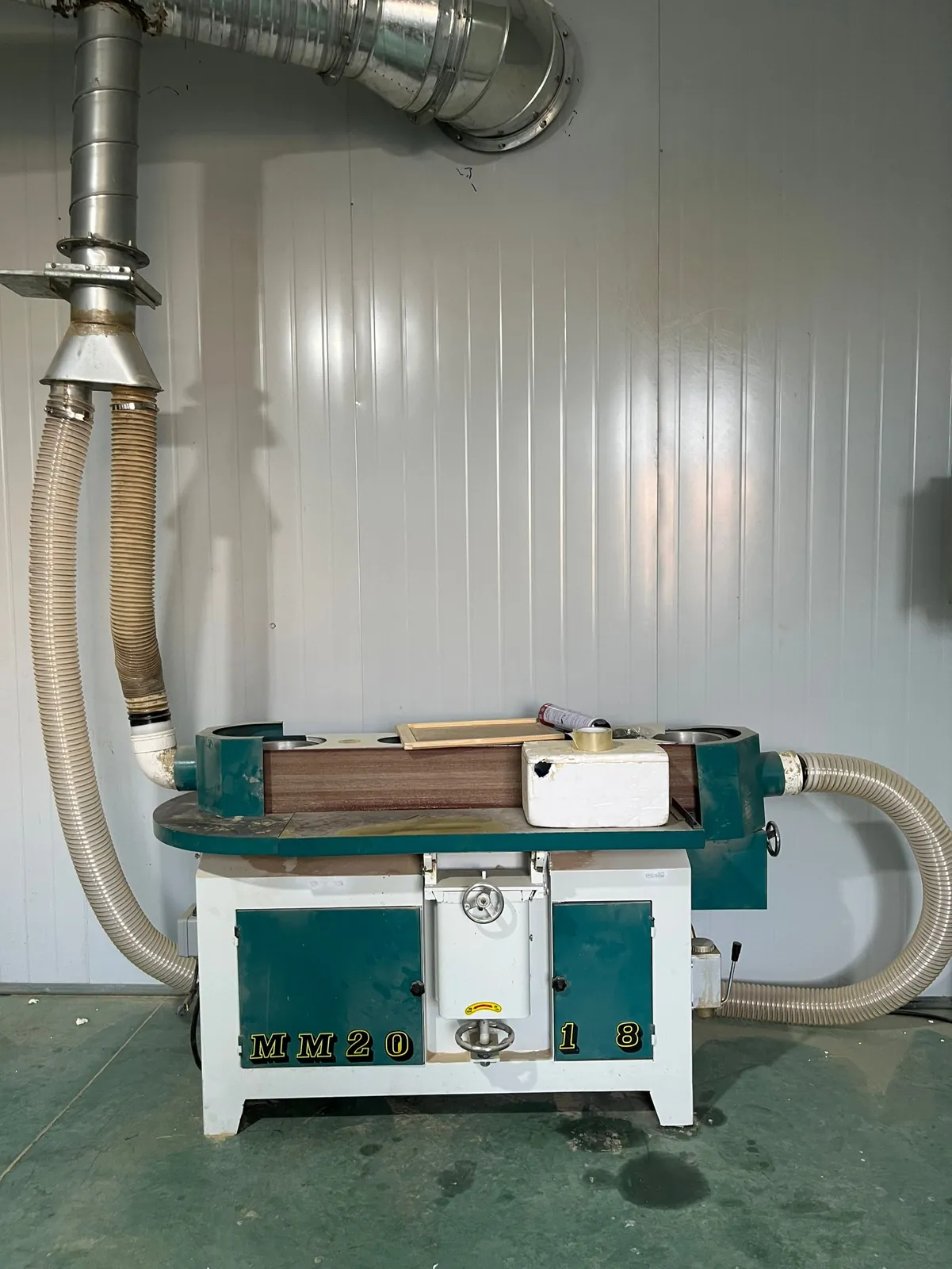 Woodworking planer-moulder machine with dust extraction hoses in the workshop