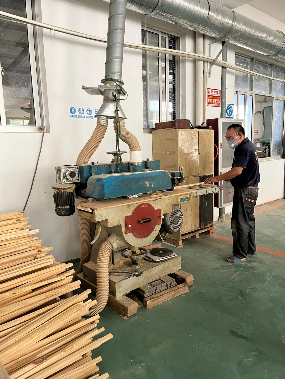 Operator feeding timber strips through a multi-blade rip saw with dust extraction
