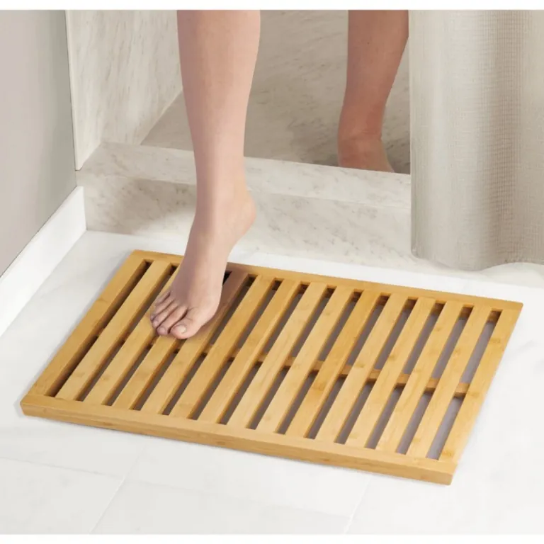 Slatted bamboo bath mat on a white bathroom floor