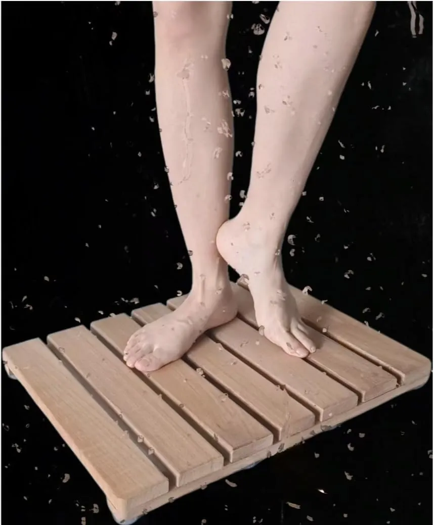 Slatted bamboo bath mat with water droplets on a dark background