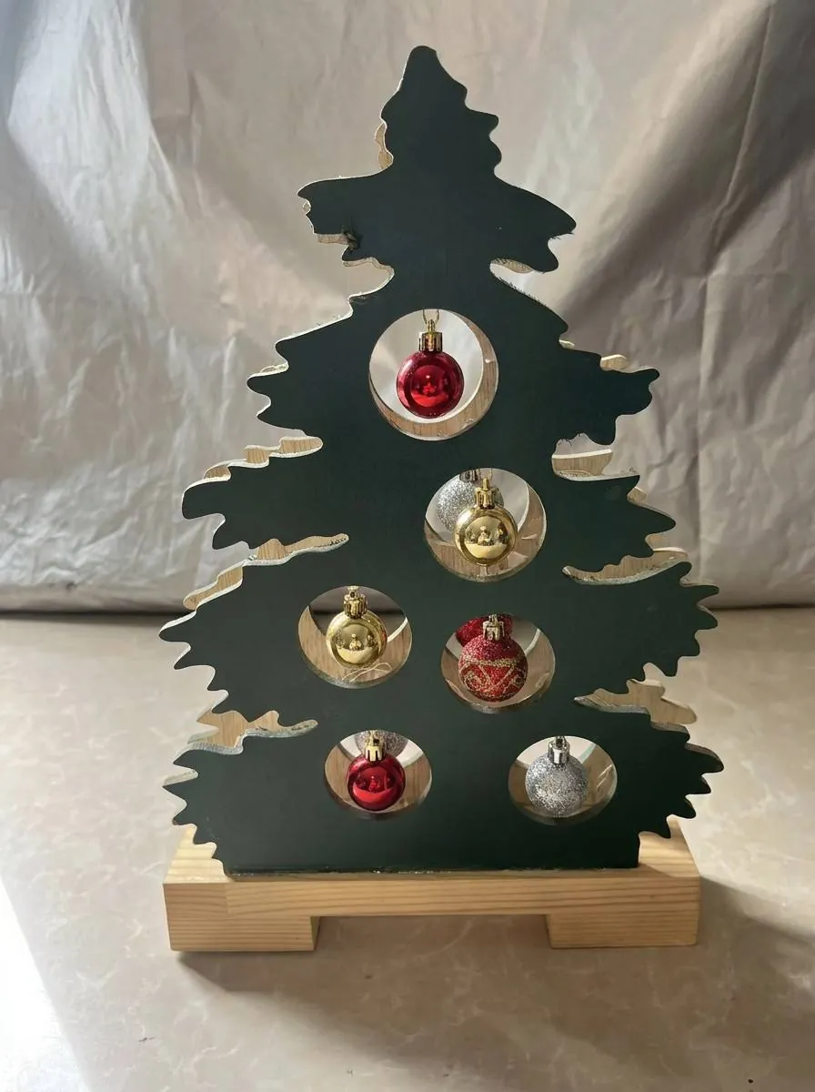 Dark green wooden Christmas tree stand-up decoration with round cut-outs holding red, gold and silver baubles