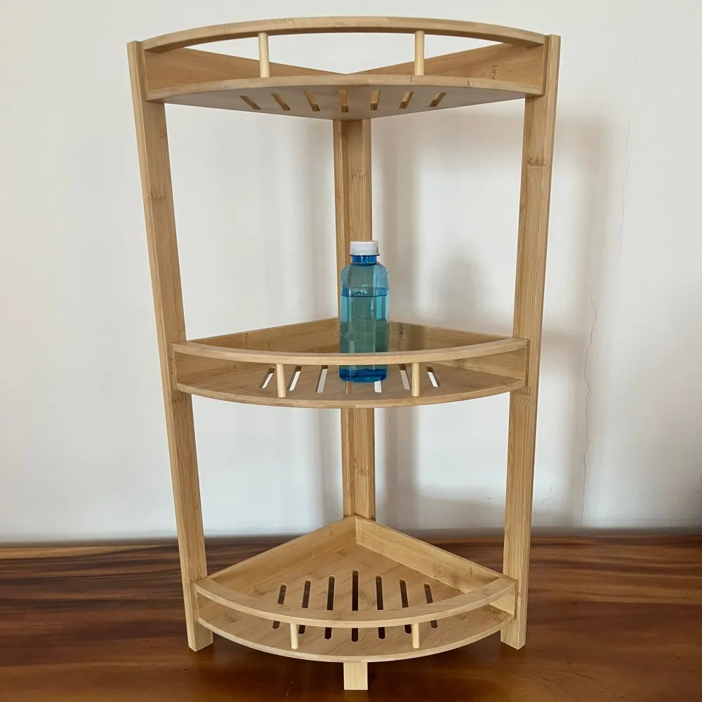 Bamboo three-tier corner shelf with slatted shelves on a wood floor